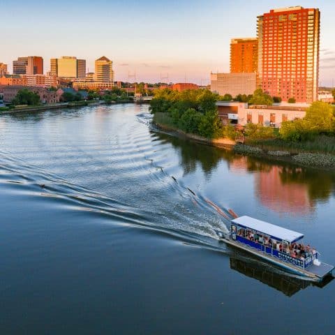 Riverfront cruise boat on water sailing past city landscape